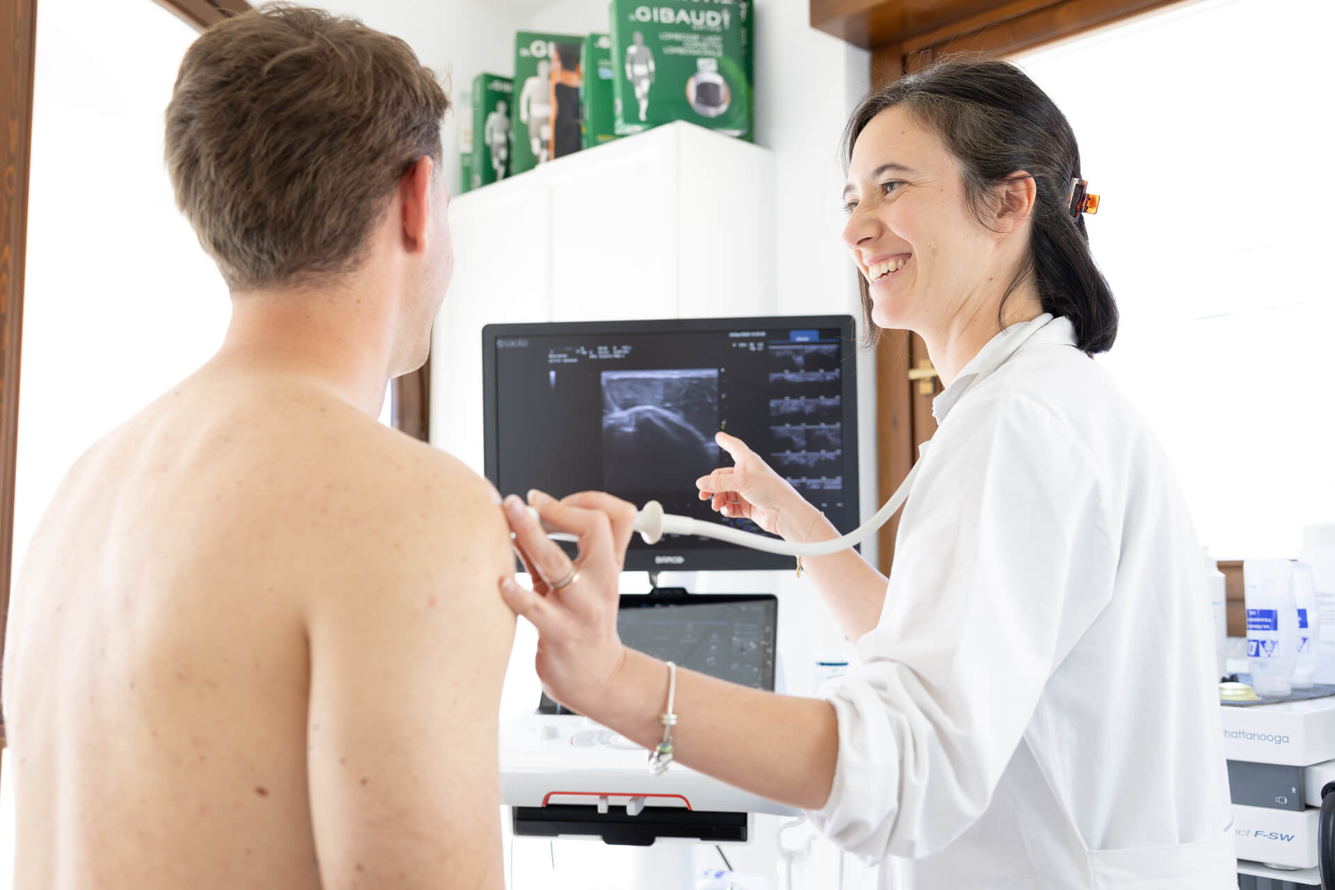 Medico esegue ecografia alla spalla del paziente durante visita specialistica al poliambulatorio