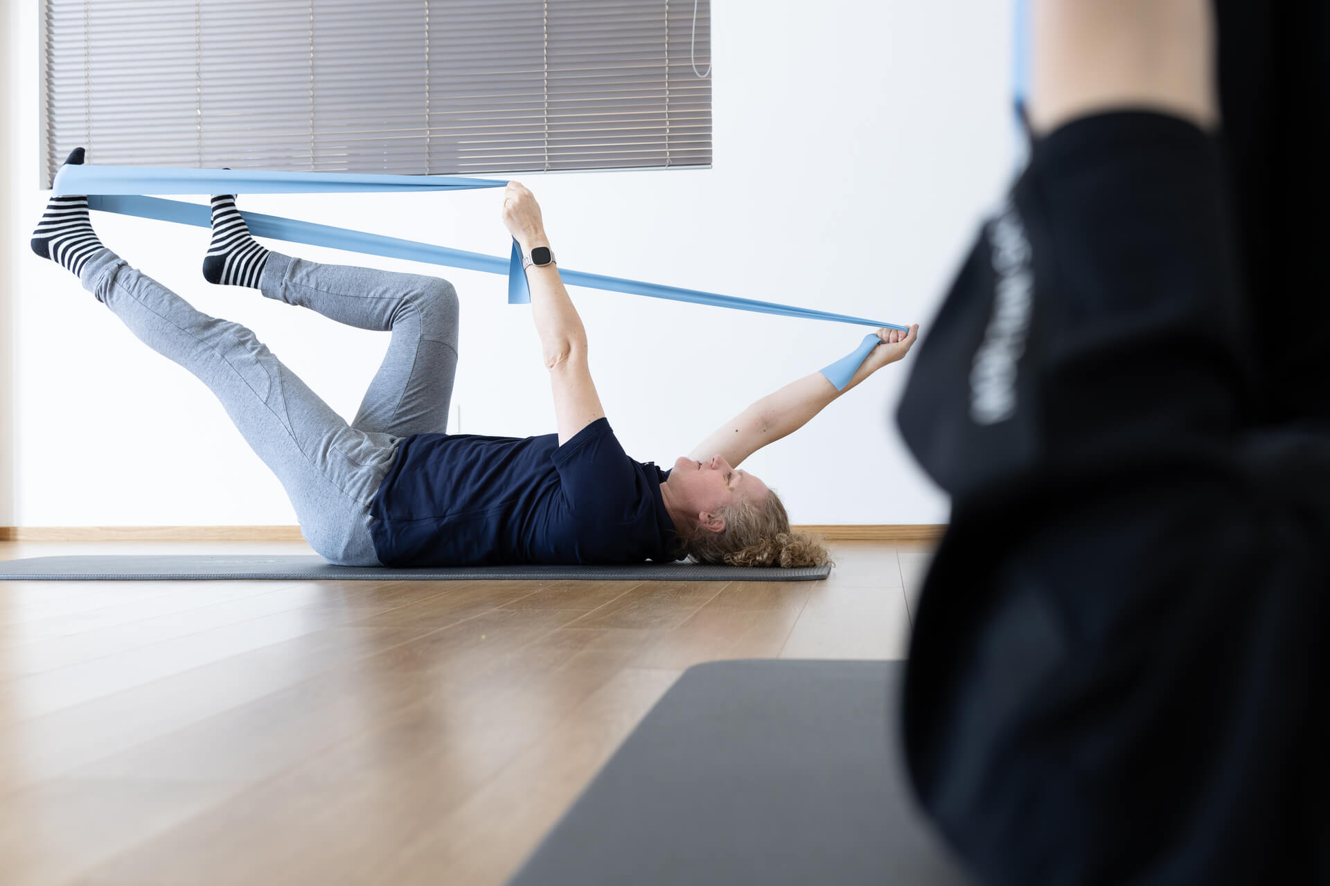 aziente esegue esercizio con elastico in posizione supina per il rinforzo di gambe e core