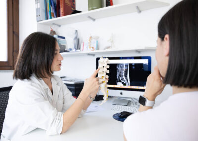 Medico mostra modello anatomico della colonna vertebrale spiegando risonanza al paziente