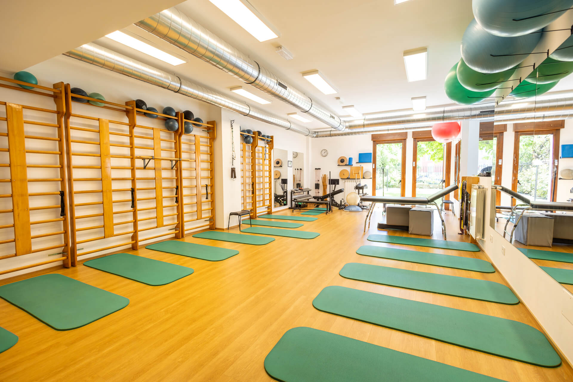 Ampia sala riabilitativa con spalliere svedesi, tappetini e attrezzature per fisioterapia di gruppo