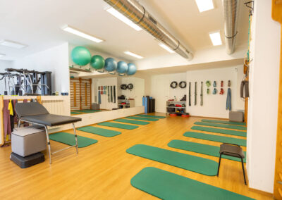 Sala riabilitativa con elastici, fitball colorate e lettino per trattamenti fisioterapici