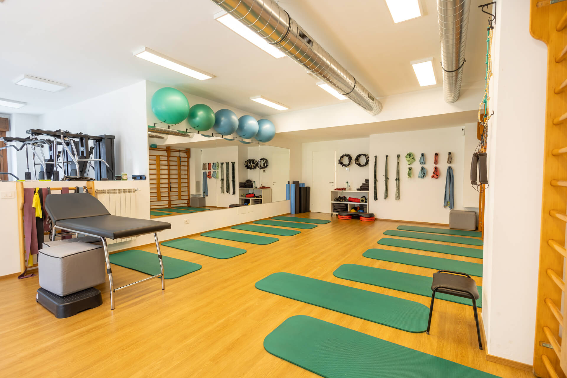 Sala riabilitativa con elastici, fitball colorate e lettino per trattamenti fisioterapici