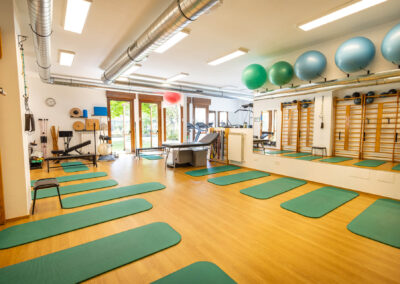 Sala fisioterapia luminosa con fitball, spalliere e tappetini verdi affacciata sul giardino