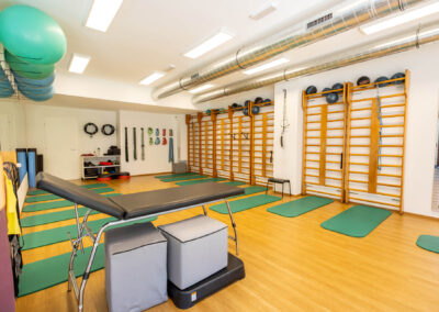 Sala di riabilitazione con lettino terapeutico, spalliere svedesi e fitball sospese