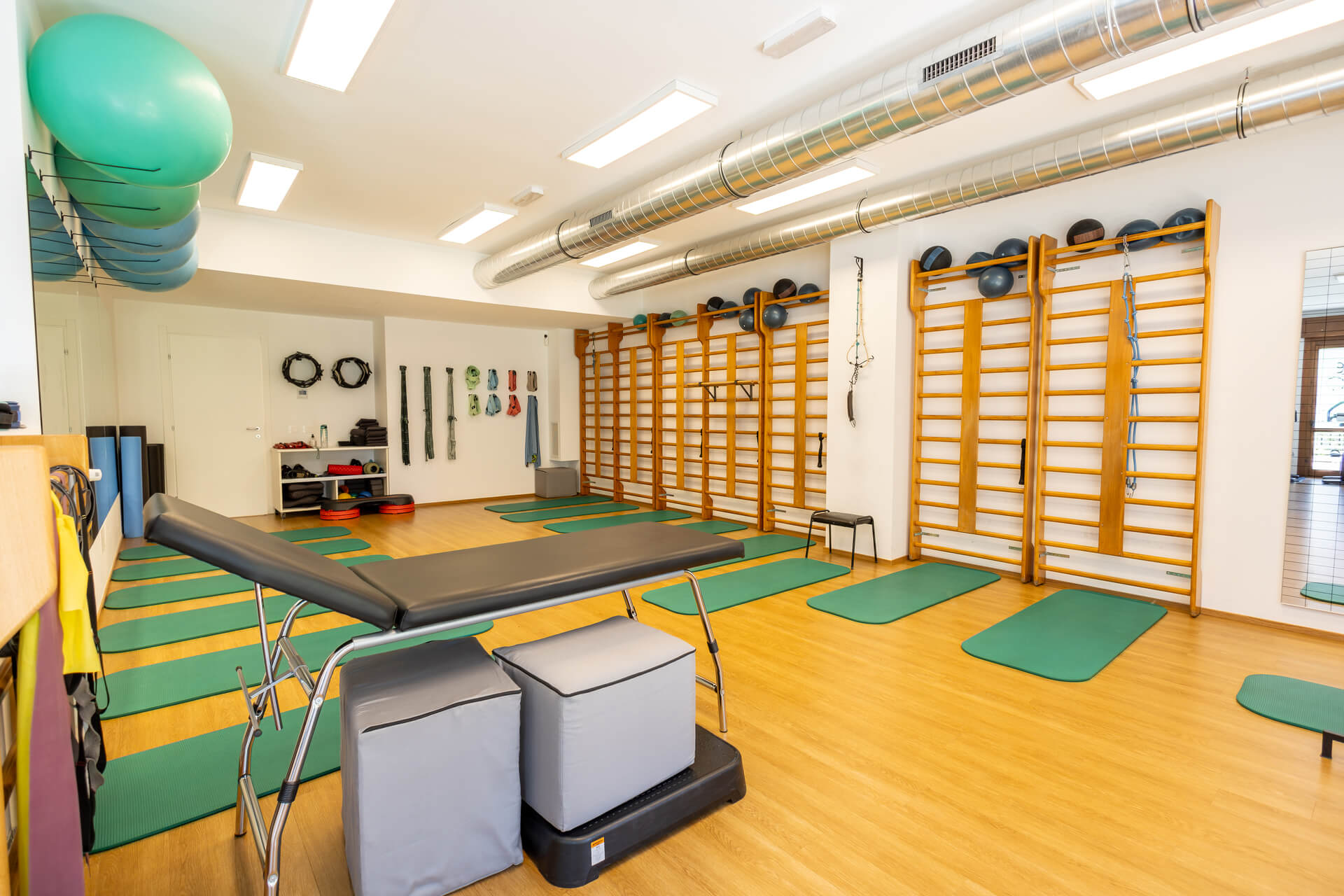 Sala di riabilitazione con lettino terapeutico, spalliere svedesi e fitball sospese