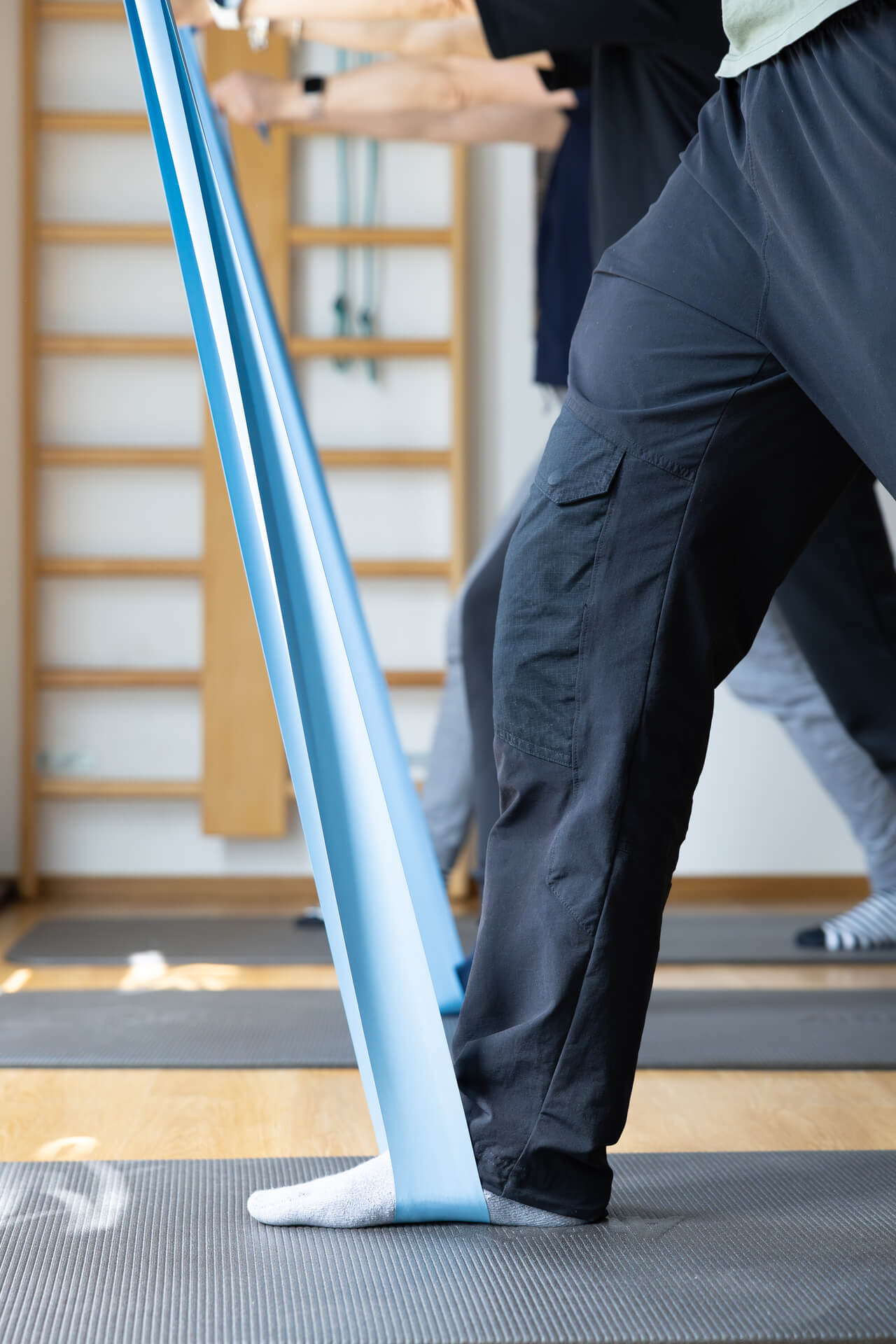 Dettaglio di esercizio di stretching alla caviglia con elastico durante seduta di gruppo